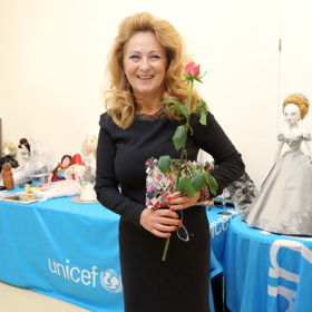 Simona Stašová nosí černé šaty s dlouhým rukávem v délce po kolena a nazouvá k nim polobotky. 