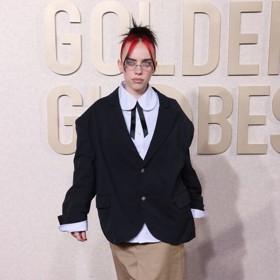 Náznaky ženskosti od Billie Eilish čekejte vždy s patřičnou přidanou hodnotou. Mary Jane střevíčky nazula s ponožkami, sukni, sako i blůzu s dívčím prvkem vázačky  pak jak jinak, než o pár čísel větší.