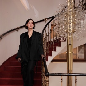 Elegantní set tvořila saténová vesta se zadním šněrováním, saténové sako s podobným šněrovacím prvkem na zádech, kalhoty s rozparkem z virgin vlny a řasená saténová sukně z hedvábí. 