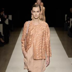 Armani pojal trendy variantu kombinace šatů a kalhot v něžném monochromatickém duchu. Vrstvení totožného materiál vyhlíží nadmíru elegantně, nepříliš široké nohavice pak pracují na zeštíhlení celé siluety.