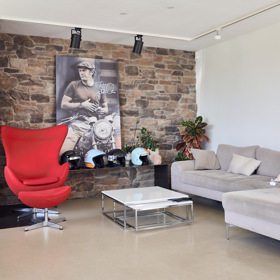 Pohled na obývací pokoj Jakuba Smolíka, kterému vévodí kamenná zeď.