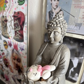 Mladý buddha se zajíčkem, penězi a oříškem. Někdy se používá jako stojánek na mobil.