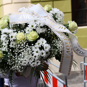 Lidé nosí květinové věnce.