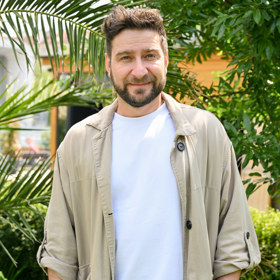 Marek Němec přišel pod Žižkovskou věž v bílém basic tričku, černých kalhotách a béžovém trenčkotu. 