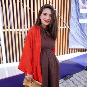 Natálie Holíková na sebe upozornila rudým kabátkem přes tmavě hnědé šaty. Detailem je nepřehlédnutelná rudá rtěnka. 