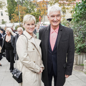 Manželka Michala Nesvadby, Andrea, oblékla béžový trenčkot doplněný o černé společenské kalhoty a černou prošívanou kabelku. 