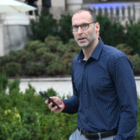 V ruce neustále držel telefon.