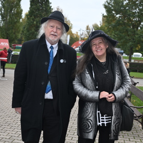 Tomuto páru to ladilo barevně. Dáma vynesla tmavý klobouk s širokou krempou, tmavý základ outfitu oživil stříbrný kabátek.