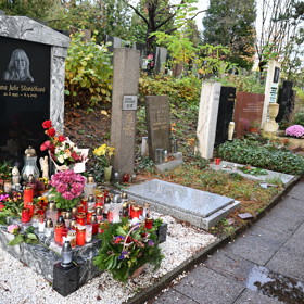 Hrob je obsypán květinami a svíčkami.