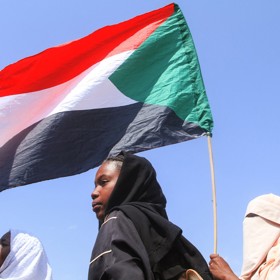 Studenti drží súdánskou vlajku během protestu proti porušování lidských práv spáchaného Jednotkami rychlé podpory (RSF).