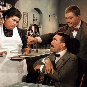 Dobrý voják Švejk: Josef Švejk - obchodník se psy a člověk s diagnózou notorického blba, který je zatčen po sarajevském atentátu a později povolán do armády. Na snímku jsou Olga Karásková, František Filipovský a Rudolf Hrušínský.