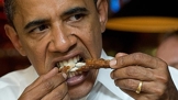 Barack Obama si pochutnává na kuřeti rukama.