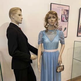 Pastelově modrá róba, doplněná perlovým náhrdelníkem. 