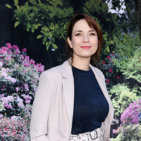 Hereččin look pak doplnilo univerzální sako v ladícím neutrálním odstínu a kontrastní tmavomodrý top, který dokonale pasoval ke vzoru na kalhotách.