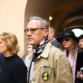 Oproti ostatním hostům měl ležerní bundu.