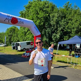 Pavel Callta s medailí pod cílovou bránou Sunrise Marathonu, který startoval už před pátou ráno.