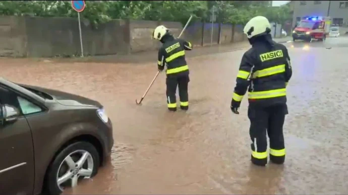 FOTO: Hasiči v zatopené ulici čistí kanalizační vpusť, aby bleskové přívaly vody mohly odtékat. – stránka 10