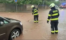 Hasiči v zatopené ulici čistí kanalizační vpusť, aby bleskové přívaly vody mohly odtékat.