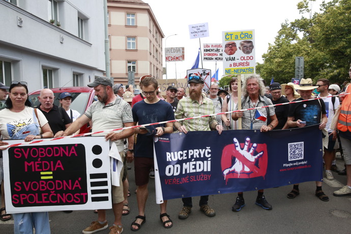 FOTO: Demonstranti v čele průvodu drží velký tmavý transparent vyzývající k ochraně veřejné služby. – stránka 1