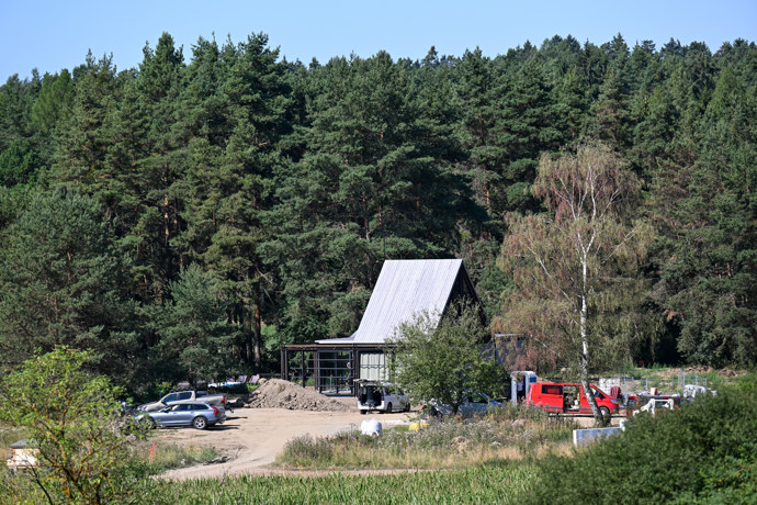FOTO: Pohled z dálky na hlavní rezidenci s výraznou strmou střechou, u níž stojí zaparkovaná auta a panuje čilý ruch. – stránka 9