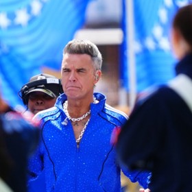 Zpěvák Robbie Williams byl v zářivě modré soupravě.